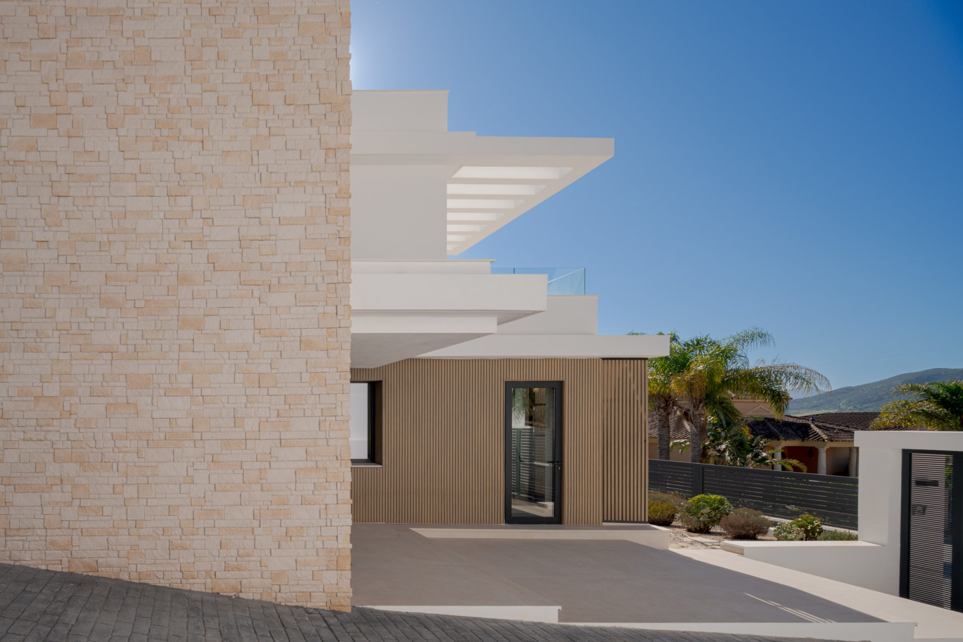 Détail matériel (pergola blanche, pierre naturelle et bois) à Villa Venetta · maison individuelle contemporaine à Cártama (Málaga) · Klic Arquitectos
