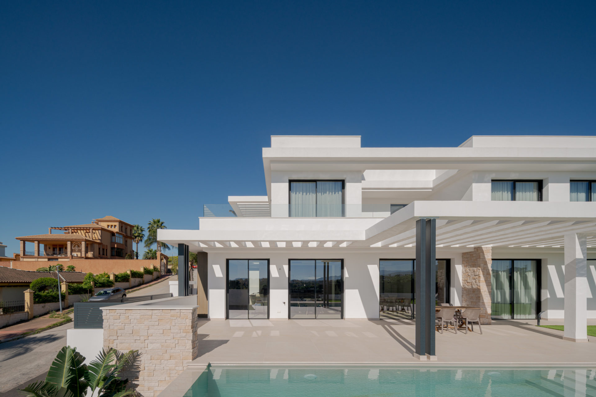 Vue latérale de Villa Venetta avec piscine, pergola blanche et jardin paysager · maison individuelle contemporaine à Cártama (Málaga) · Klic Arquitectos