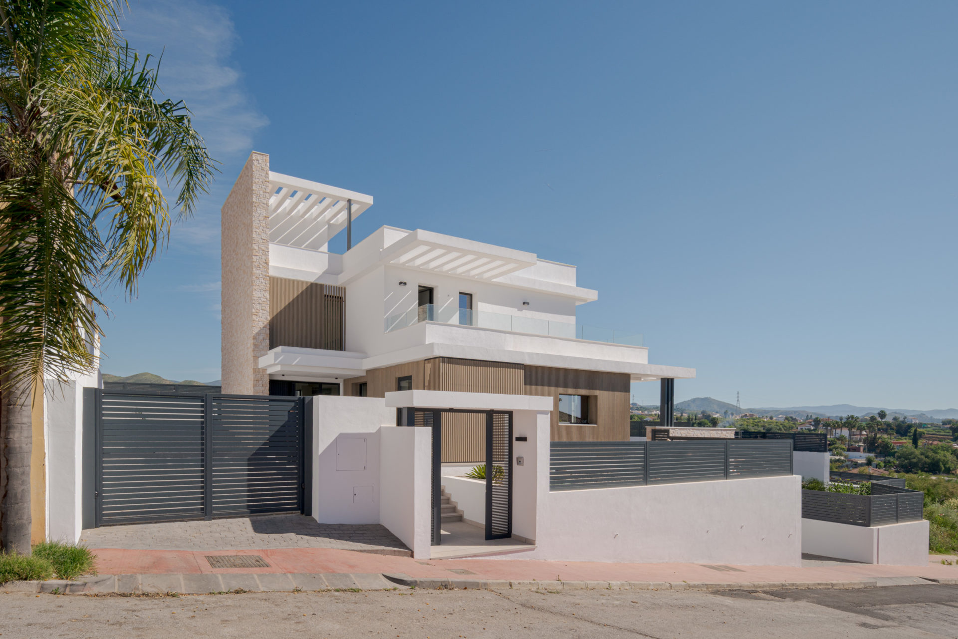 Entrée piétonne avec portail et palmiers à Villa Venetta · façade de maison individuelle contemporaine à Cártama (Málaga) · Klic Arquitectos
