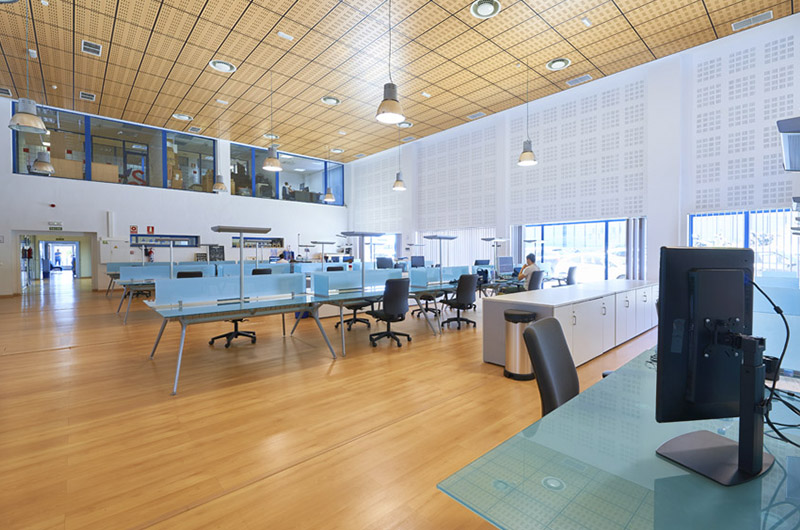 Arbeitssaal des Coworking PROMÁLAGA CW im Technologiepark von Andalusien mit Doppelhöhe, Technikmezzanin und Trennwänden aus blauem Einscheibensicherheitsglas von Klic Arquitectos