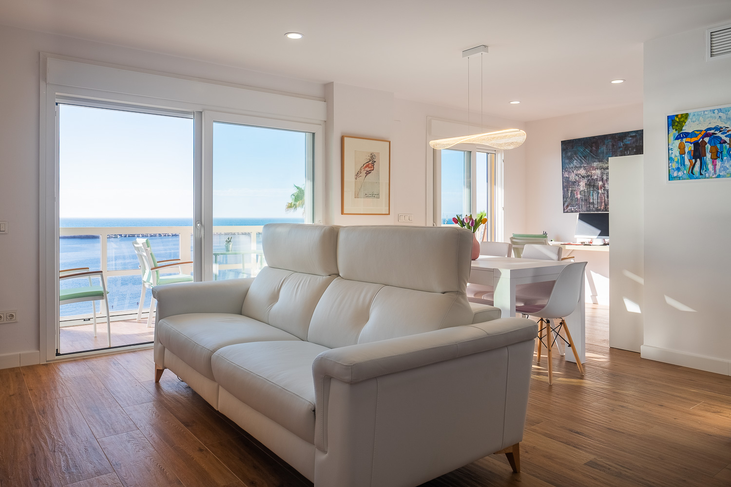 Salón con sofá blanco frente al mar de Casa T&A, reforma con interiorismo en el Paseo Marítimo de Fuengirola (Málaga) por Klic Arquitectos