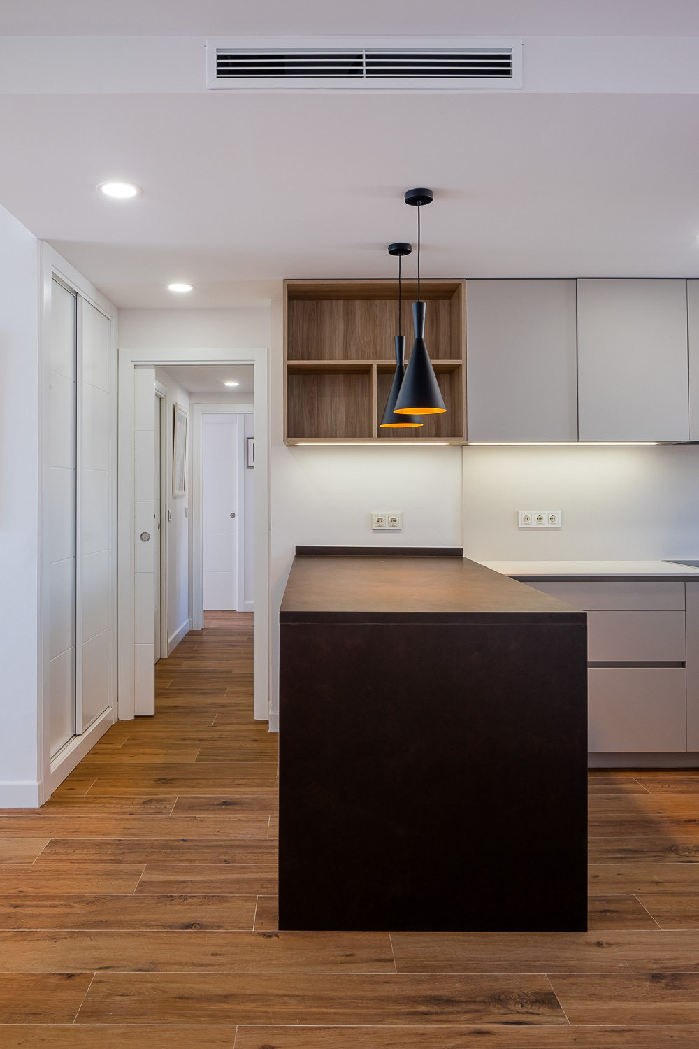 Cocina con pasillo de Casa T&A, reforma con interiorismo en el Paseo Marítimo de Fuengirola (Málaga) por Klic Arquitectos