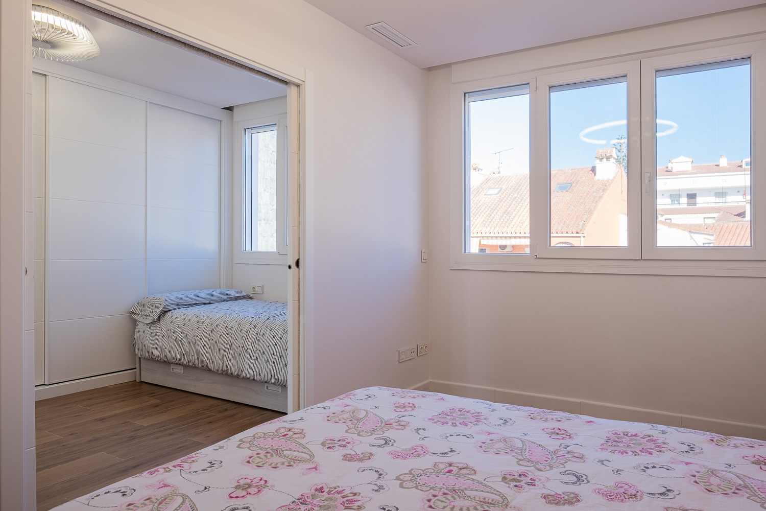 Dormitorio con corredera oculta de Casa T&A, reforma con interiorismo en el Paseo Marítimo de Fuengirola (Málaga) por Klic Arquitectos