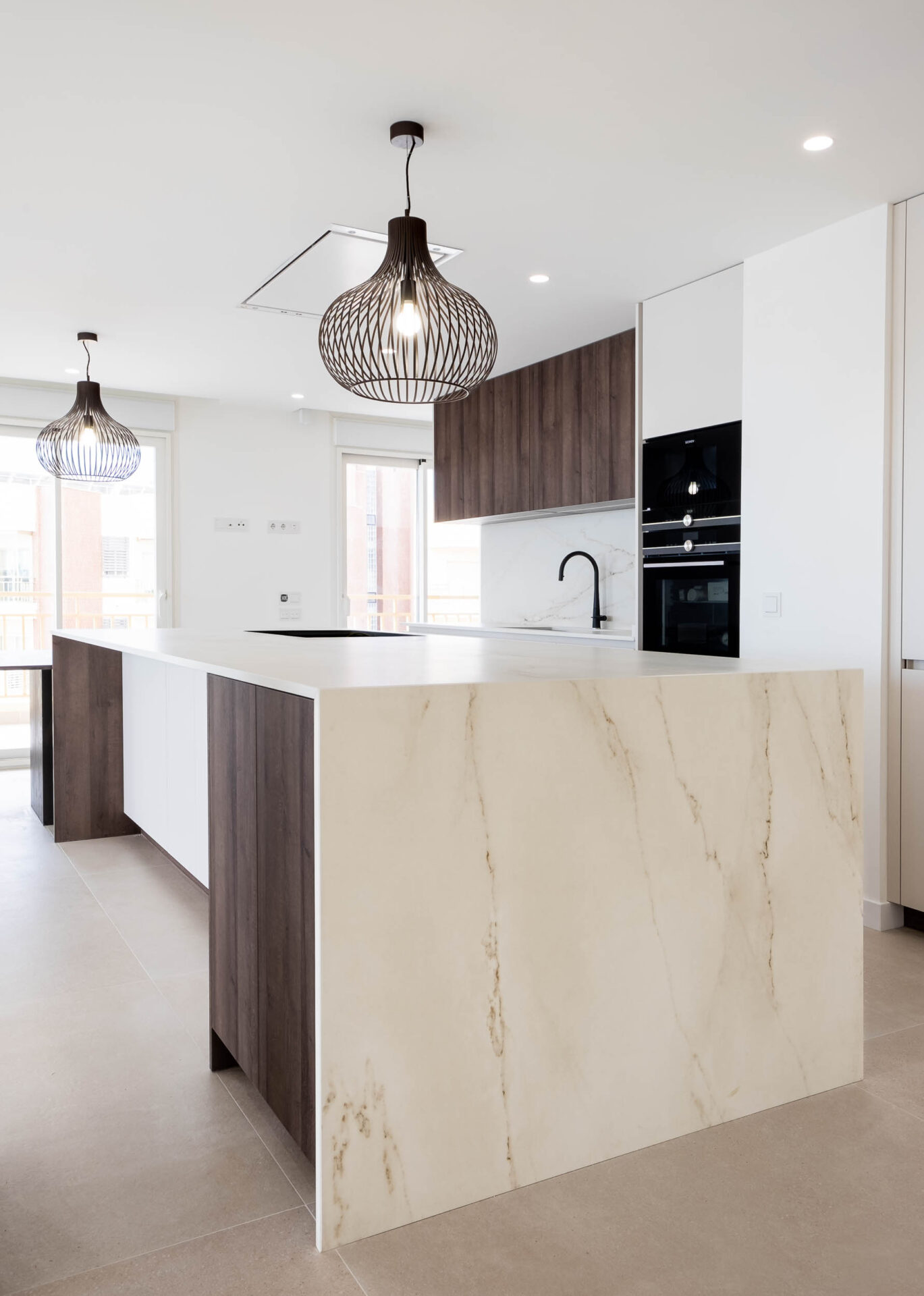 Cocina con isla de mármol y muebles en madera · reforma Pº Marítimo Rey de España 3 (Fuengirola) por Klic Arquitectos