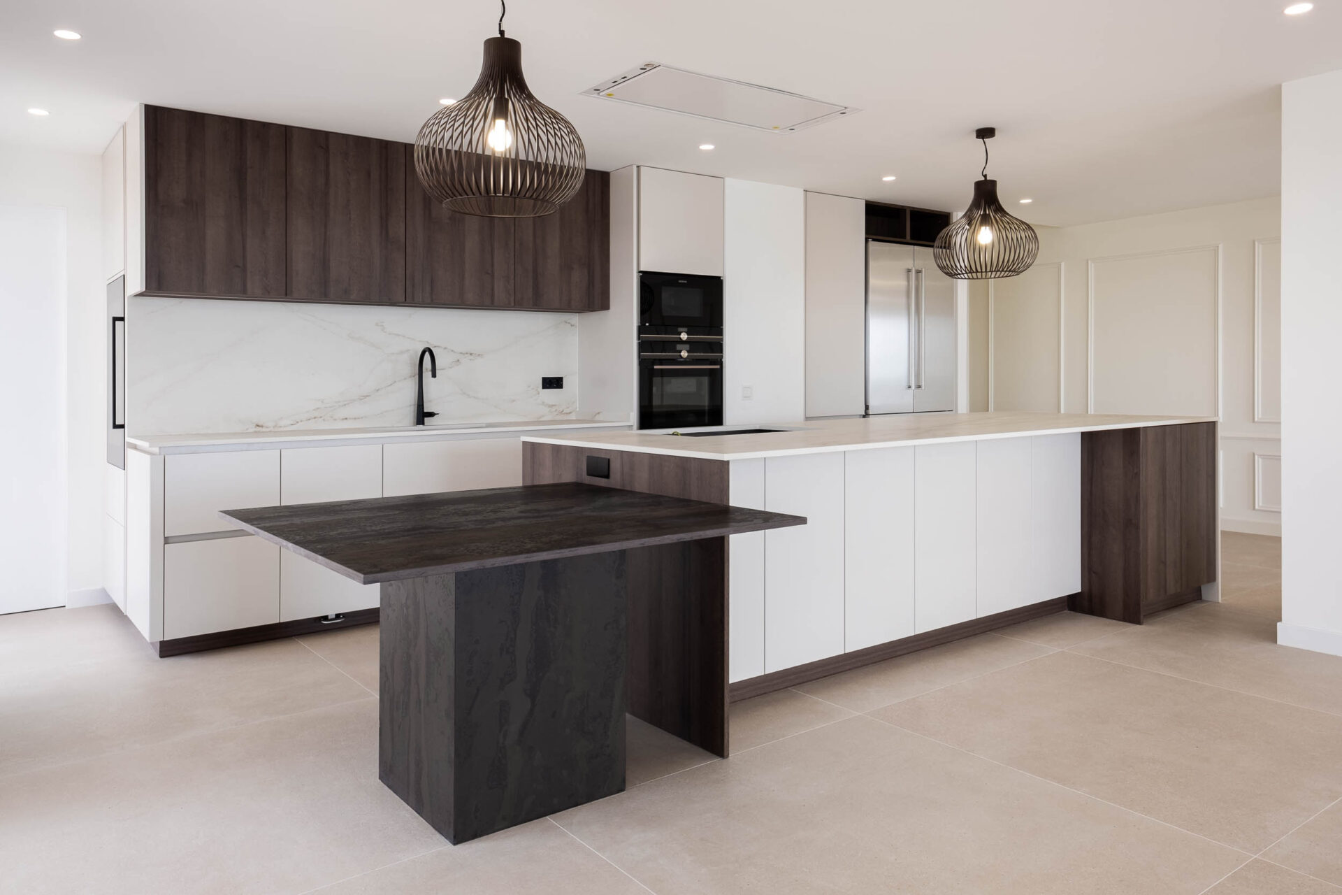 Cocina con isla central, barra alta y muebles de madera oscura · reforma Pº Marítimo Rey de España 3 (Fuengirola) por Klic Arquitectos