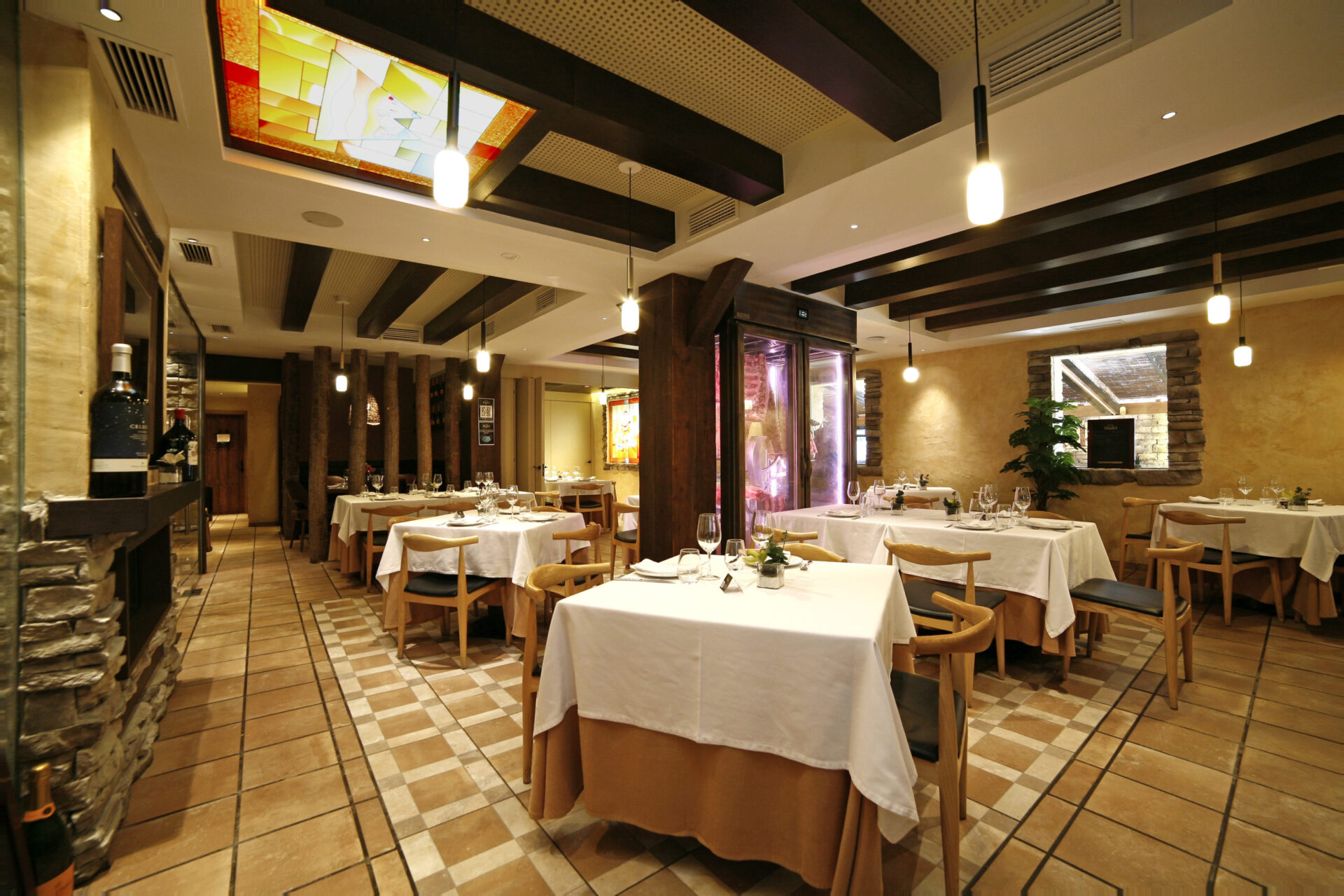 Speisesaal des Asador Iñaki in der Calle Ayala, Málaga mit polychromem Keramik-Oberlicht, Stammsäulen und Fischgrätboden von Klic Arquitectos