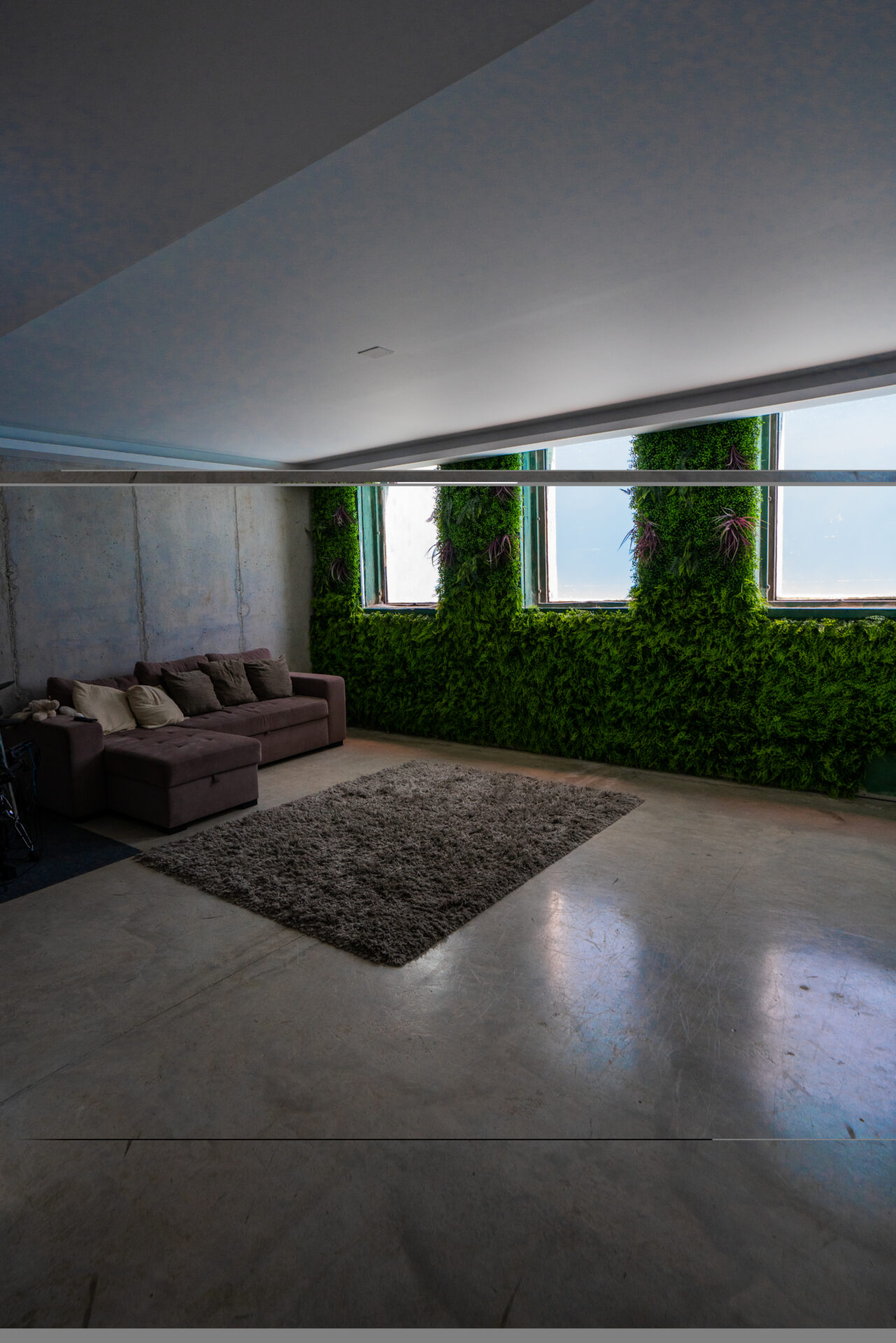 Salón con jardín vertical y hormigón visto de Casa Maravillas en Benalmádena Costa (Málaga) por Klic Arquitectos