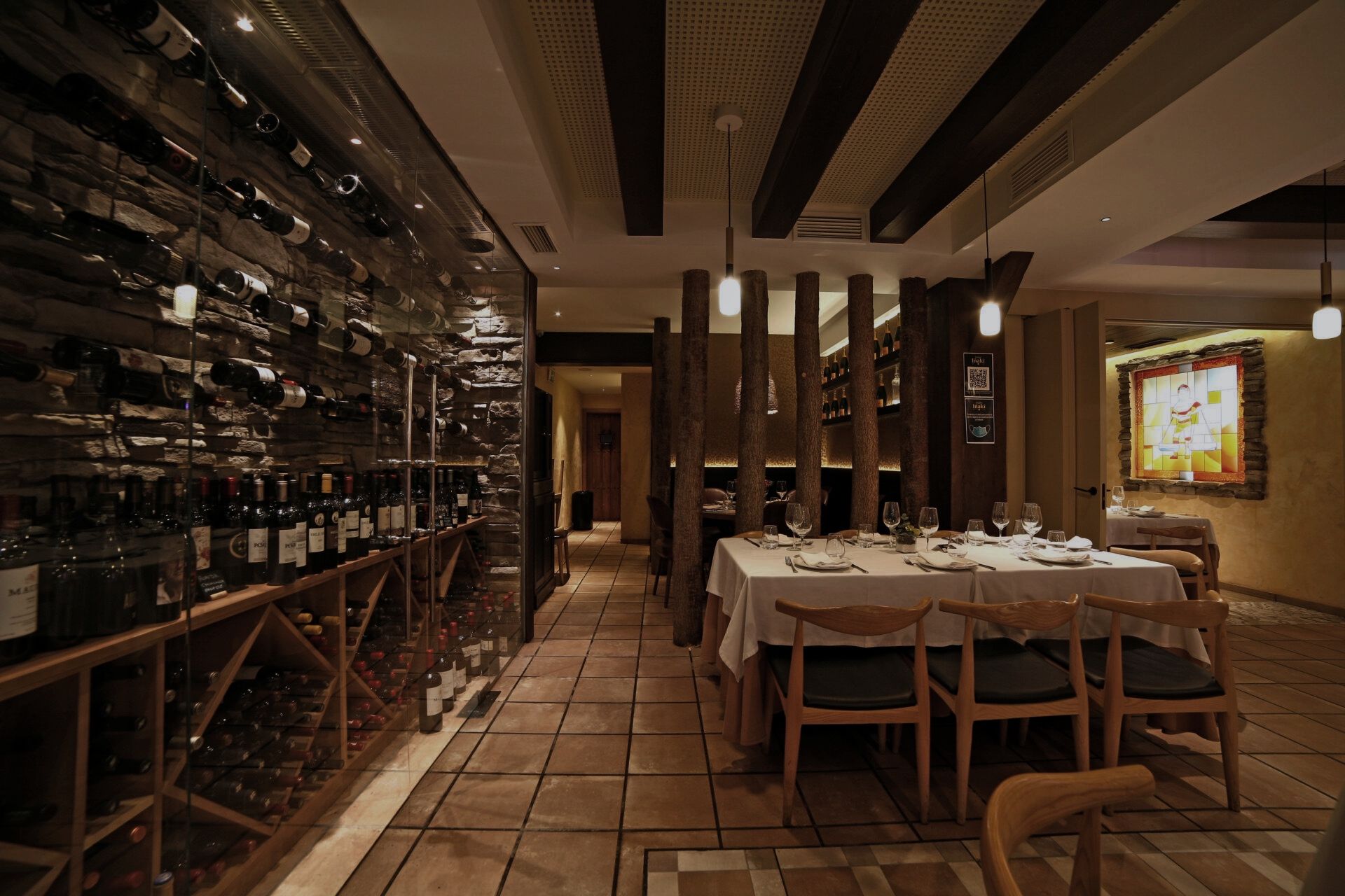 Tienda de vinos con paredes de botellas y mesa de madera, proyecto retail por Klic Arquitectos