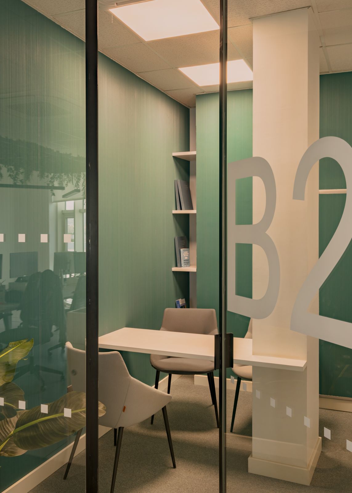 Booth privado de trabajo con vinilo B2 y pared verde, oficinas Solbyte por Klic Arquitectos